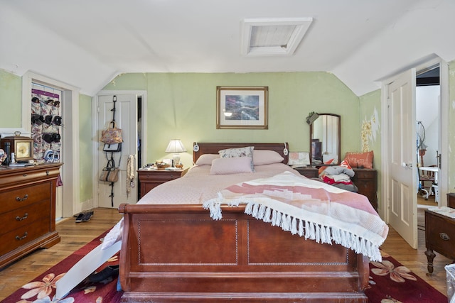 bedroom featuring light wood-type flooring and vaulted ceiling