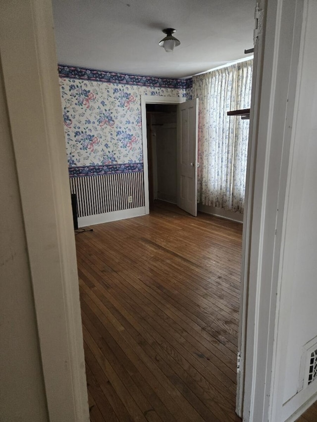 unfurnished room with wallpapered walls, baseboards, and hardwood / wood-style flooring