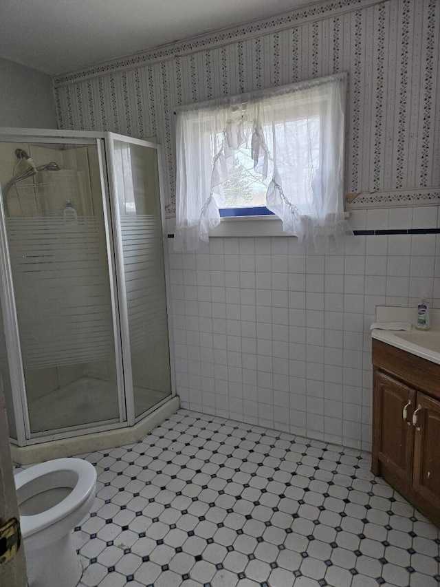 bathroom featuring tile patterned floors, toilet, a stall shower, and vanity