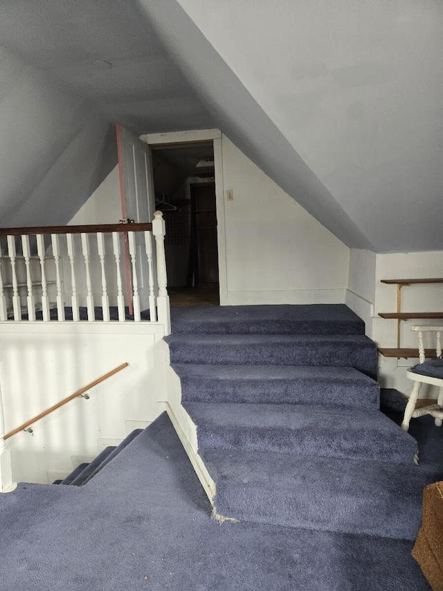 stairs featuring carpet flooring and vaulted ceiling