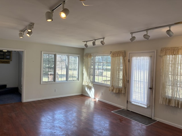 interior space featuring track lighting, wood finished floors, and baseboards