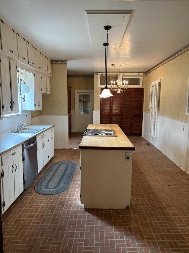 kitchen with stainless steel dishwasher, wainscoting, and brick patterned floor