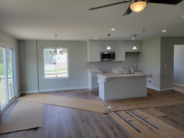 kitchen featuring pendant lighting, white cabinets, a kitchen island with sink, and a healthy amount of sunlight