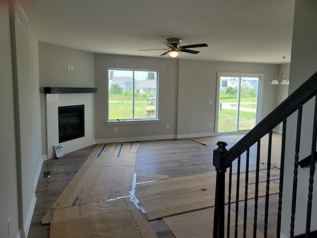 unfurnished living room featuring ceiling fan with notable chandelier and hardwood / wood-style floors