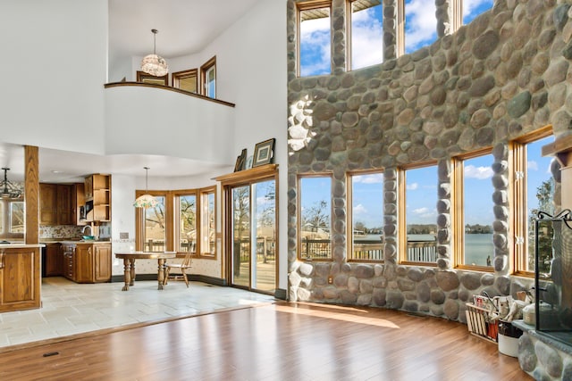 unfurnished living room featuring a high ceiling, light hardwood / wood-style flooring, and plenty of natural light