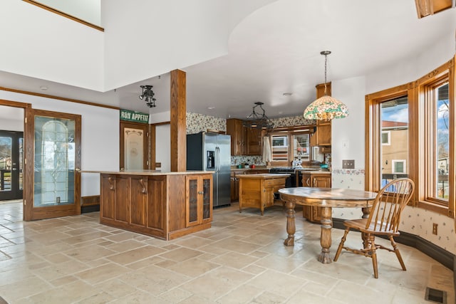 kitchen with tasteful backsplash, kitchen peninsula, stainless steel fridge with ice dispenser, and hanging light fixtures