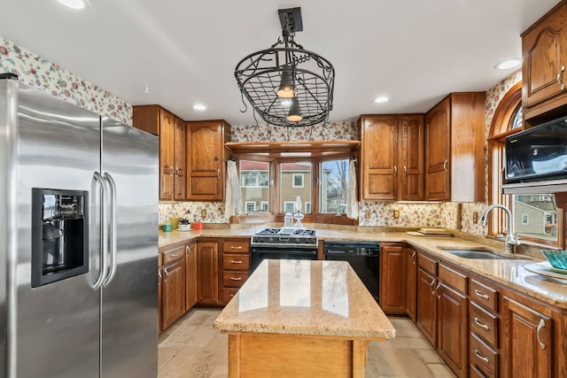 kitchen featuring light stone counters, sink, black appliances, decorative light fixtures, and a kitchen island