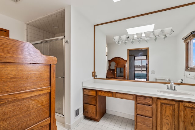 bathroom with tile patterned floors, a skylight, vanity, and a shower with shower door