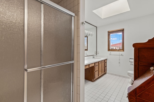 bathroom featuring a skylight, tile patterned floors, vanity, a shower with door, and toilet