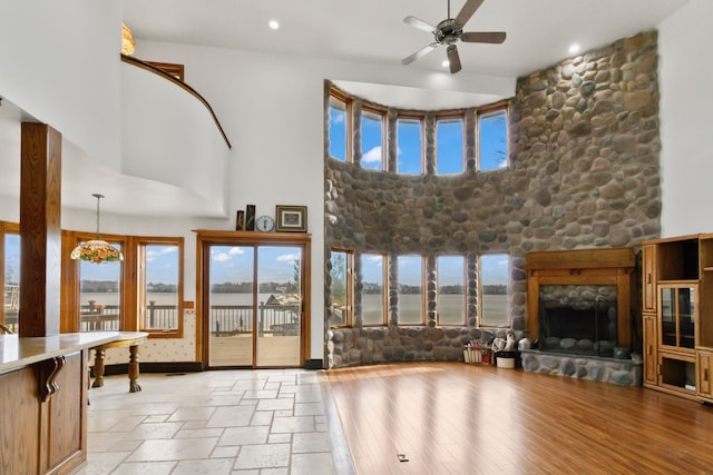 living room featuring a fireplace, a high ceiling, light wood-type flooring, and ceiling fan