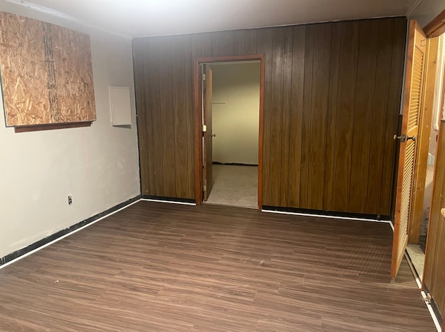 unfurnished room featuring wooden walls and dark wood-type flooring