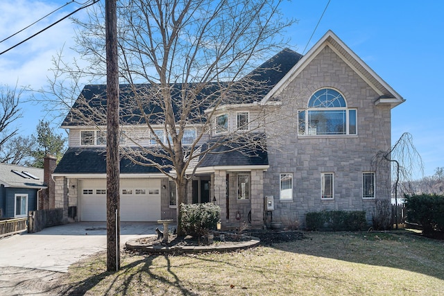 traditional-style home with an attached garage, a shingled roof, fence, concrete driveway, and a front yard