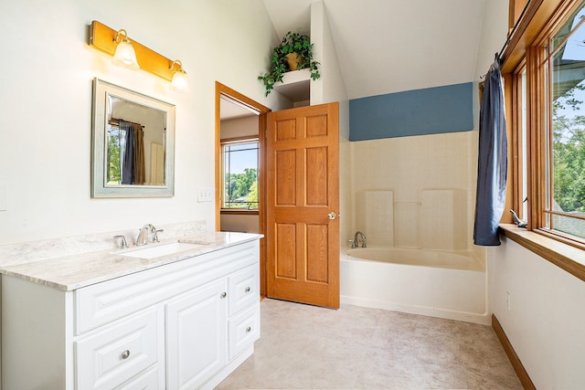 bathroom featuring a tub, vanity, and vaulted ceiling