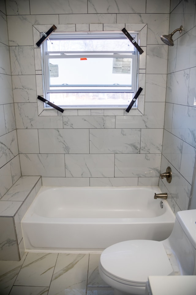 bathroom featuring plenty of natural light, toilet, and tiled shower / bath combo