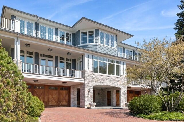 49106 Sun Valley Falls Blvd, New Buffalo, MI 49117 - view of front of house with stone siding, a balcony, a garage, and decorative driveway