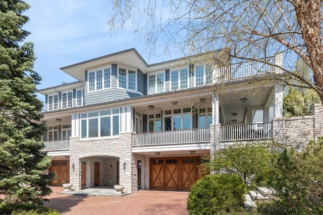 49106 Sun Valley Falls Blvd, New Buffalo, MI 49117 - view of front facade featuring stone siding, a balcony, a garage, and decorative driveway