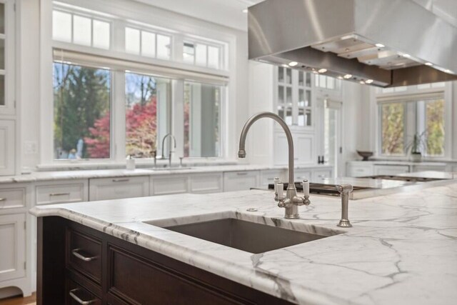 49106 Sun Valley Falls Blvd, New Buffalo, MI 49117 - kitchen with a sink, wall chimney exhaust hood, white cabinets, light stone counters, and dark brown cabinetry