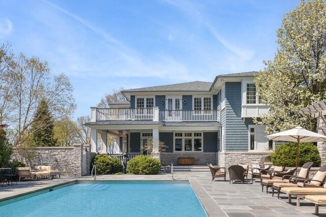 49106 Sun Valley Falls Blvd, New Buffalo, MI 49117 - back of property featuring a balcony, a patio area, stone siding, and an outdoor pool