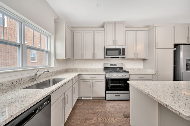 kitchen with light stone countertops, sink, dark hardwood / wood-style floors, and appliances with stainless steel finishes