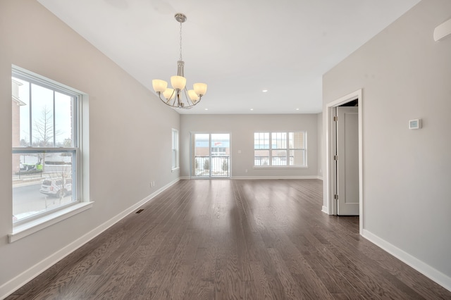 spare room with a chandelier and dark hardwood / wood-style floors