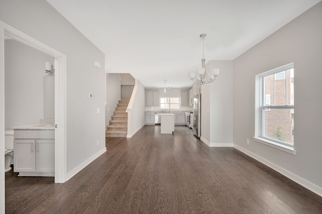 unfurnished living room with dark hardwood / wood-style flooring and an inviting chandelier