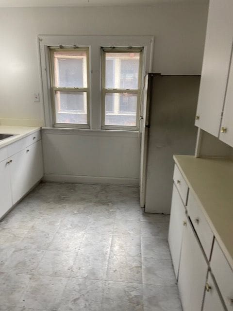 kitchen featuring stainless steel fridge and white cabinetry