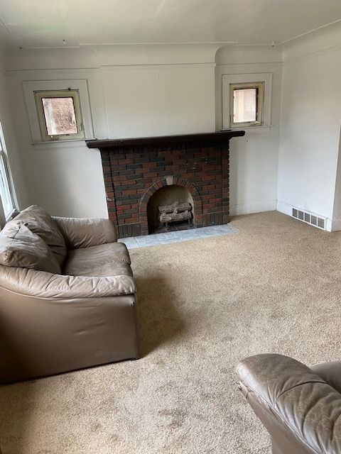 living room featuring carpet flooring and a brick fireplace