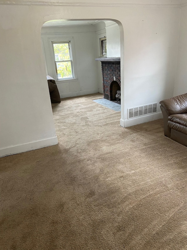 unfurnished living room featuring a fireplace, carpet, and crown molding