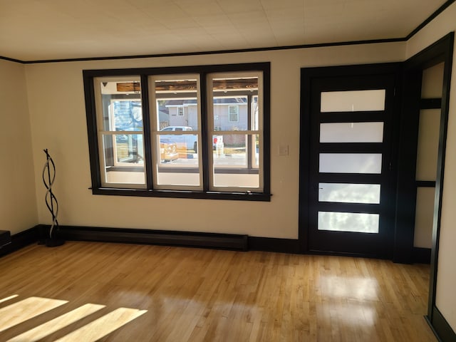 entrance foyer featuring light wood-type flooring, ornamental molding, and a baseboard radiator