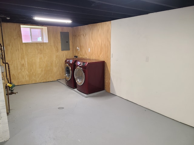 basement with wooden walls, independent washer and dryer, and electric panel