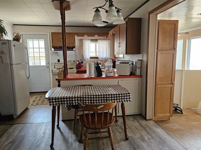 kitchen with backsplash, white appliances, pendant lighting, a chandelier, and light hardwood / wood-style floors