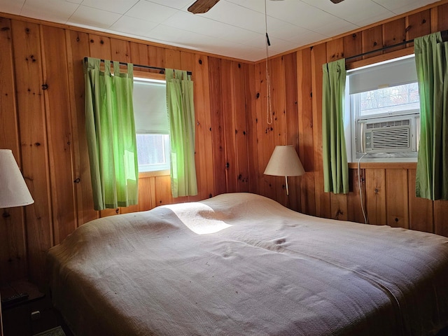 bedroom featuring cooling unit, wooden walls, and multiple windows