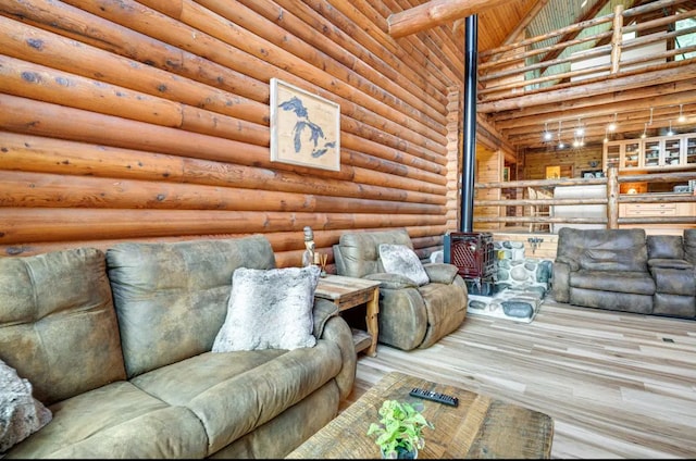 living room featuring log walls, hardwood / wood-style floors, high vaulted ceiling, and a wood stove