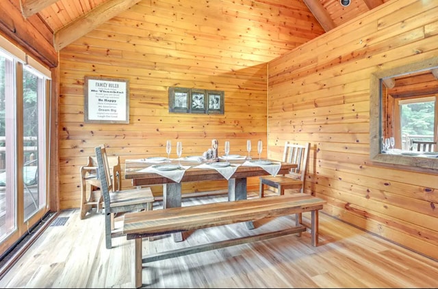 dining room with lofted ceiling with beams, a healthy amount of sunlight, wooden ceiling, and light hardwood / wood-style flooring