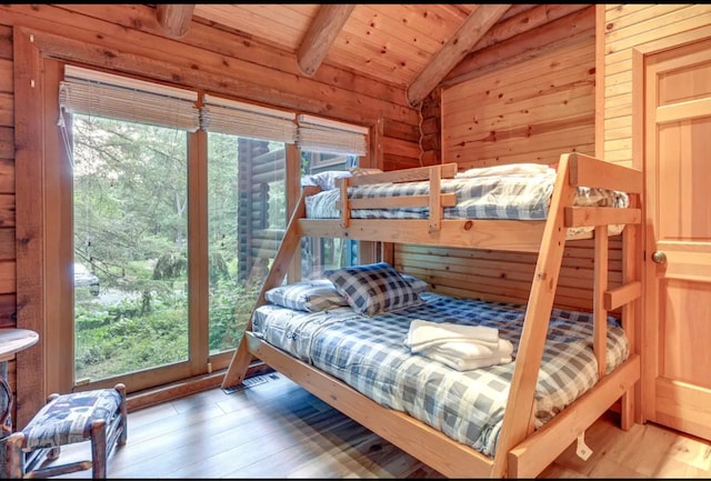 bedroom featuring hardwood / wood-style floors, lofted ceiling with beams, and multiple windows