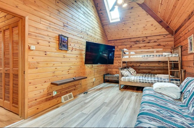 unfurnished bedroom with light hardwood / wood-style floors, wood ceiling, wooden walls, and a skylight