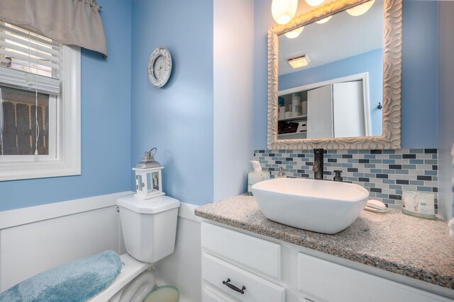 bathroom featuring vanity, toilet, and backsplash