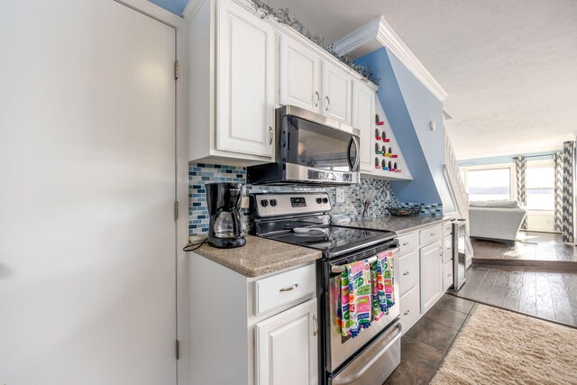 kitchen with white cabinetry, dark wood-type flooring, stainless steel appliances, backsplash, and crown molding