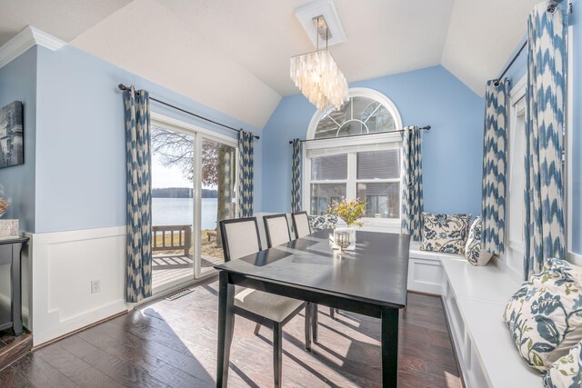 dining room with a notable chandelier, dark hardwood / wood-style floors, a water view, and lofted ceiling