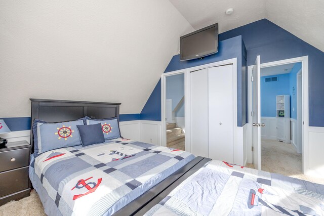 carpeted bedroom with a closet, a textured ceiling, and vaulted ceiling