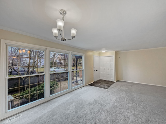 unfurnished living room featuring dark colored carpet, crown molding, and a notable chandelier