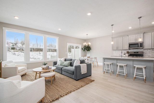 living room featuring sink, a chandelier, and light wood-type flooring