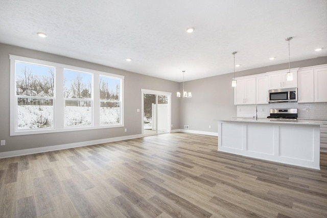 kitchen with sink, hanging light fixtures, stainless steel appliances, tasteful backsplash, and white cabinets