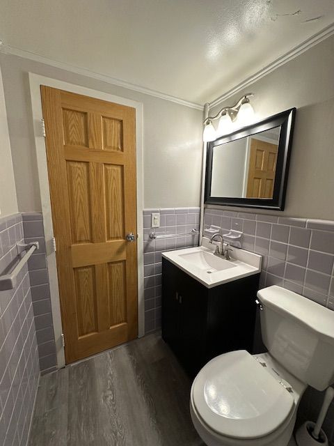 bathroom featuring crown molding, hardwood / wood-style floors, vanity, and tile walls