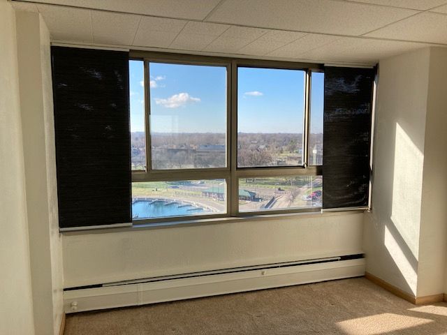 unfurnished room with carpet, a drop ceiling, and a baseboard heating unit