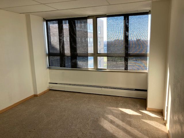 empty room featuring carpet, a drop ceiling, and a baseboard heating unit