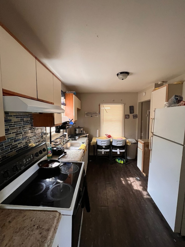 kitchen featuring backsplash, plenty of natural light, dark hardwood / wood-style flooring, and white appliances