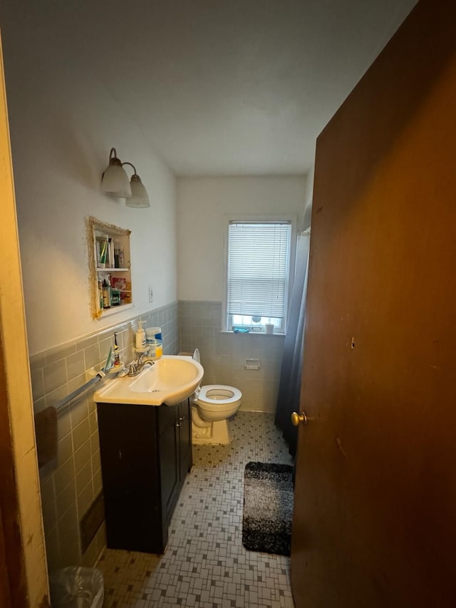 bathroom featuring vanity, tile walls, and toilet