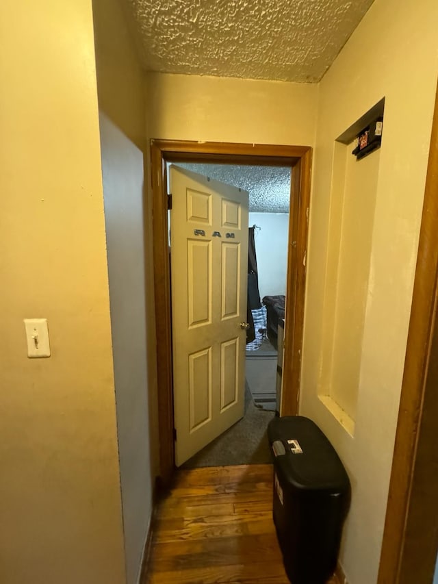 corridor with dark wood-type flooring and a textured ceiling