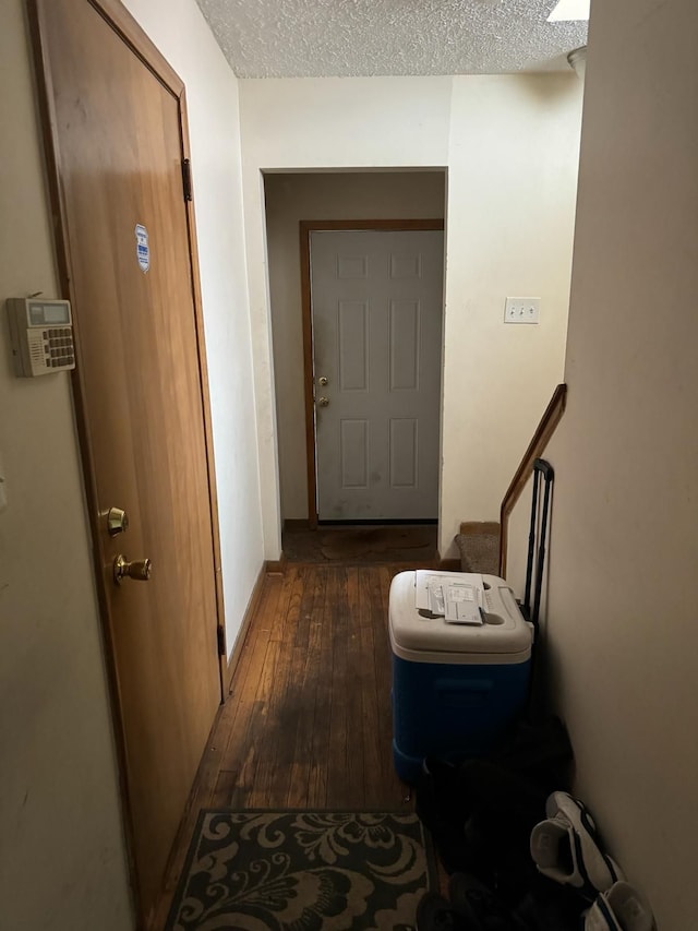 hall featuring a textured ceiling and dark hardwood / wood-style floors